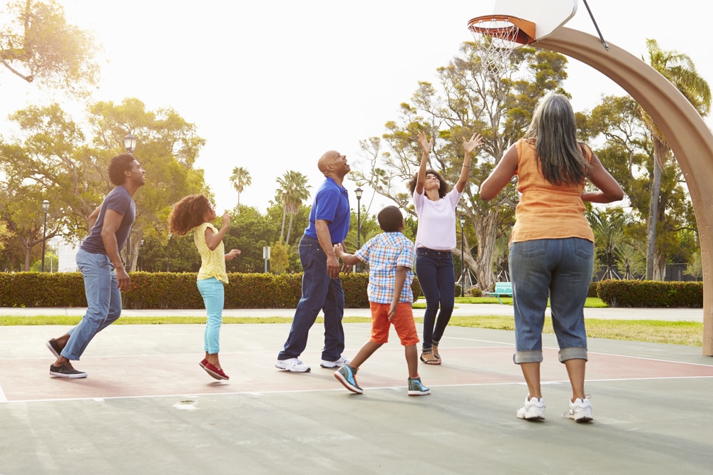 Multi-generational family playing basketball on outdoor athletic court