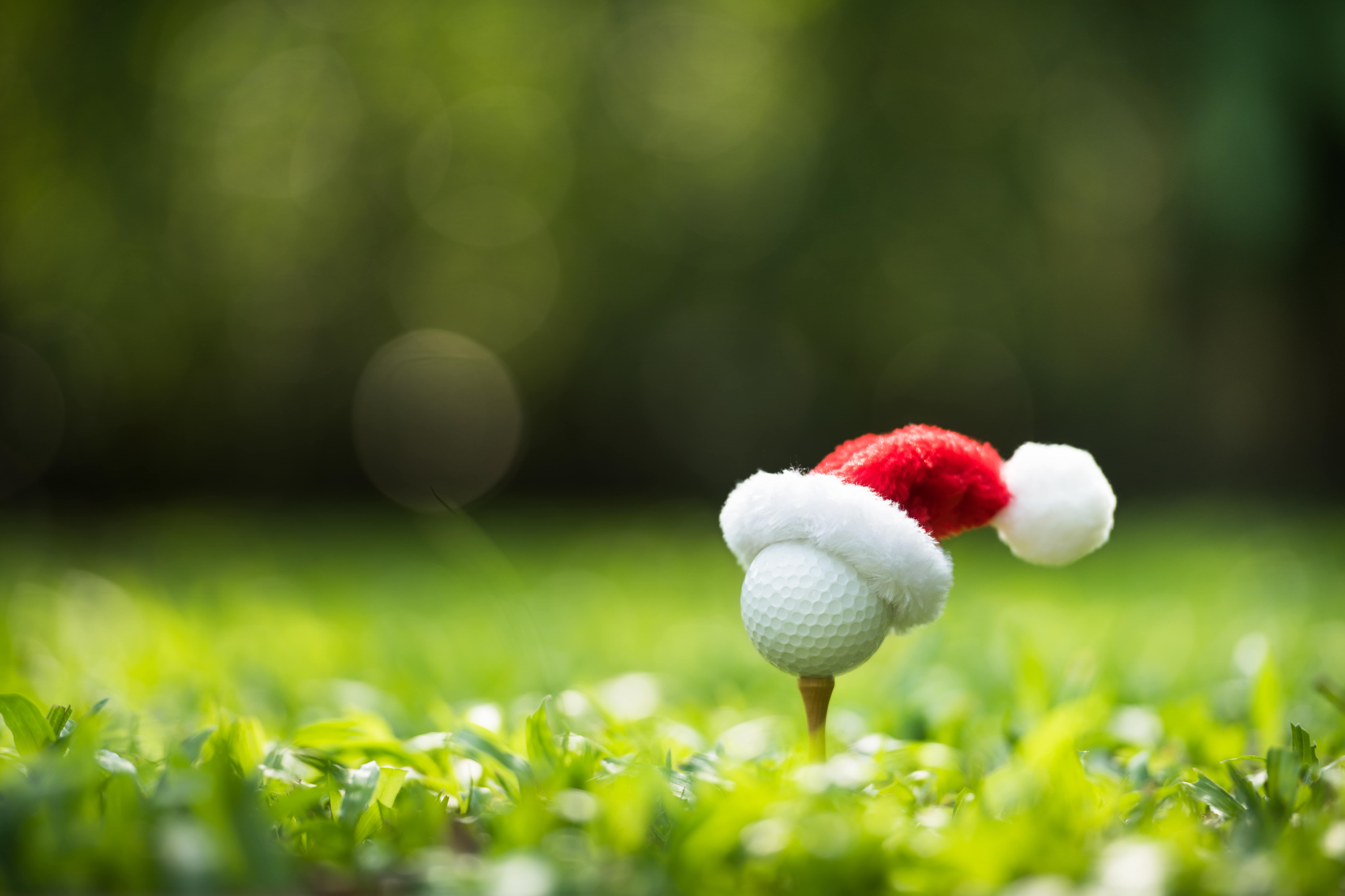 Golf ball on tee wearing santa hat